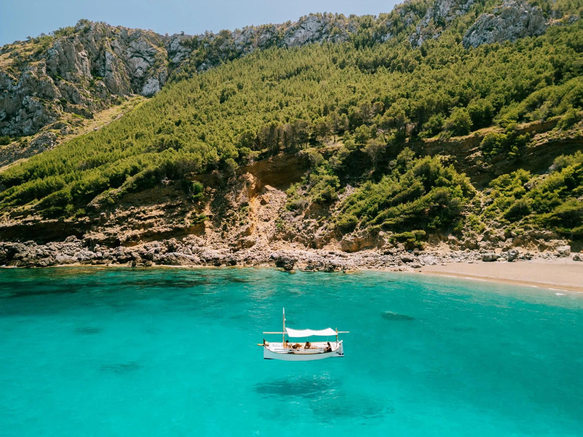 El llaüt Na Rumba fondeado en una cala turquesa del norte de Mallorca, boat charter y excursiones